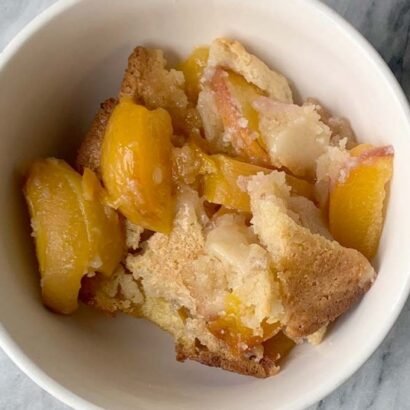 A-bowl-of-lazy-homemade-peach-cobbler-on-marble-cutting-board